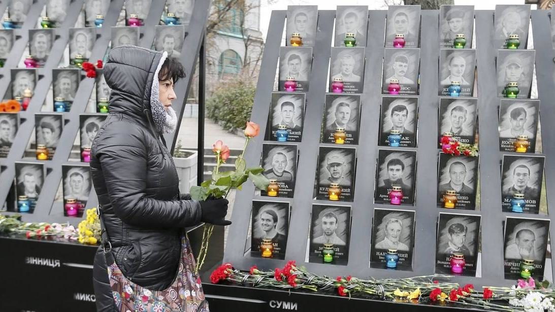 Een vrouw legt bloemen neer bij het herdenkingsmonument voor de slachtoffers van de anti-regeringsprotesten op het Maidanplein in Kiev