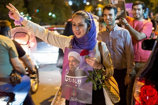 Iraanse vrouw met een campagneposter van president Hassan Rouhani