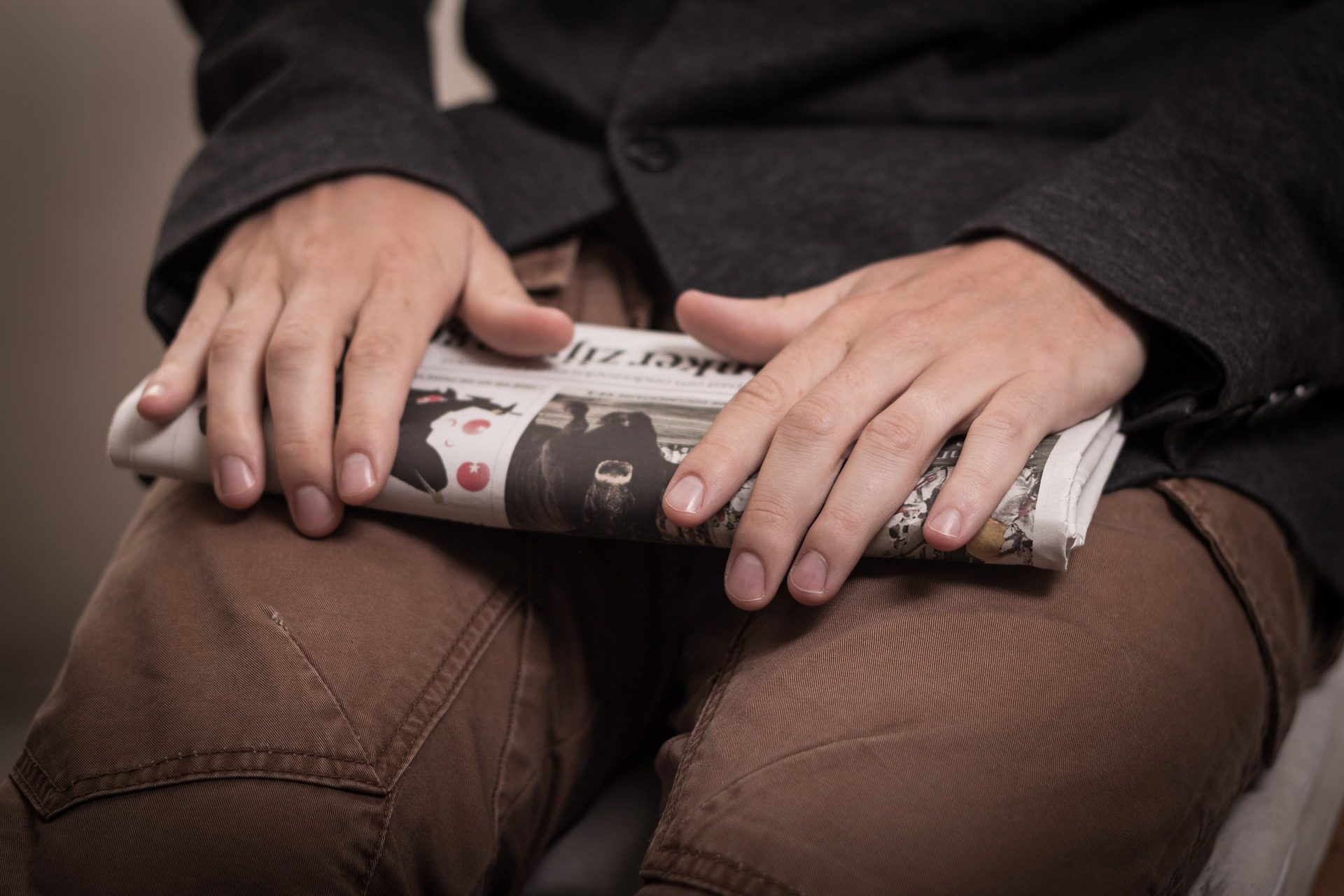 guy holding newspaper on lap