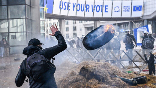 Demonstrant gooit een brandende autoband naar de politie tijdens de protestactie van boeren in de Europese wijk in Brussel, België.